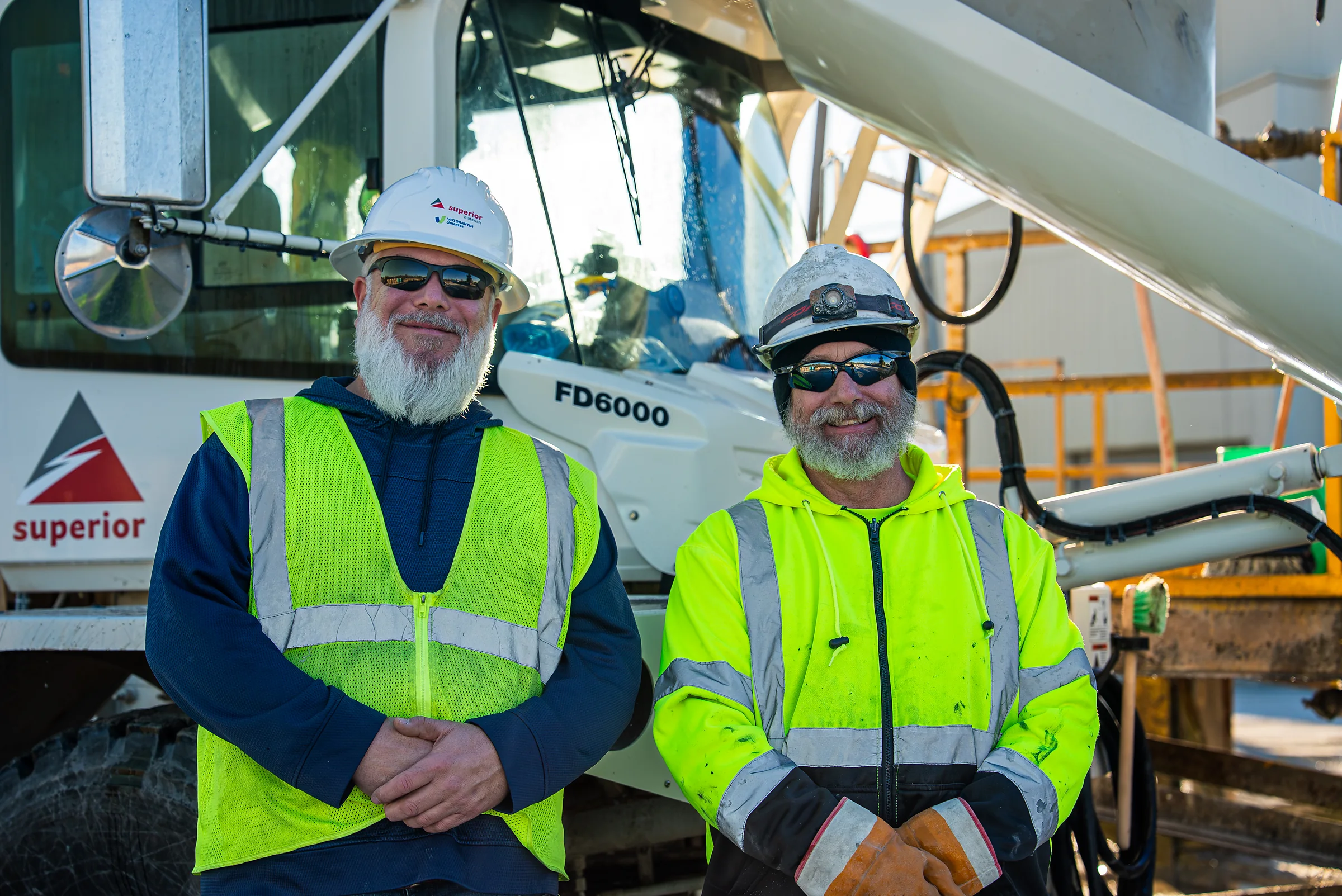 Superior Materials' Ready-mix Concrete - two drivers in hard hats and hi-vis gear in front of a front discharge mixer truck
