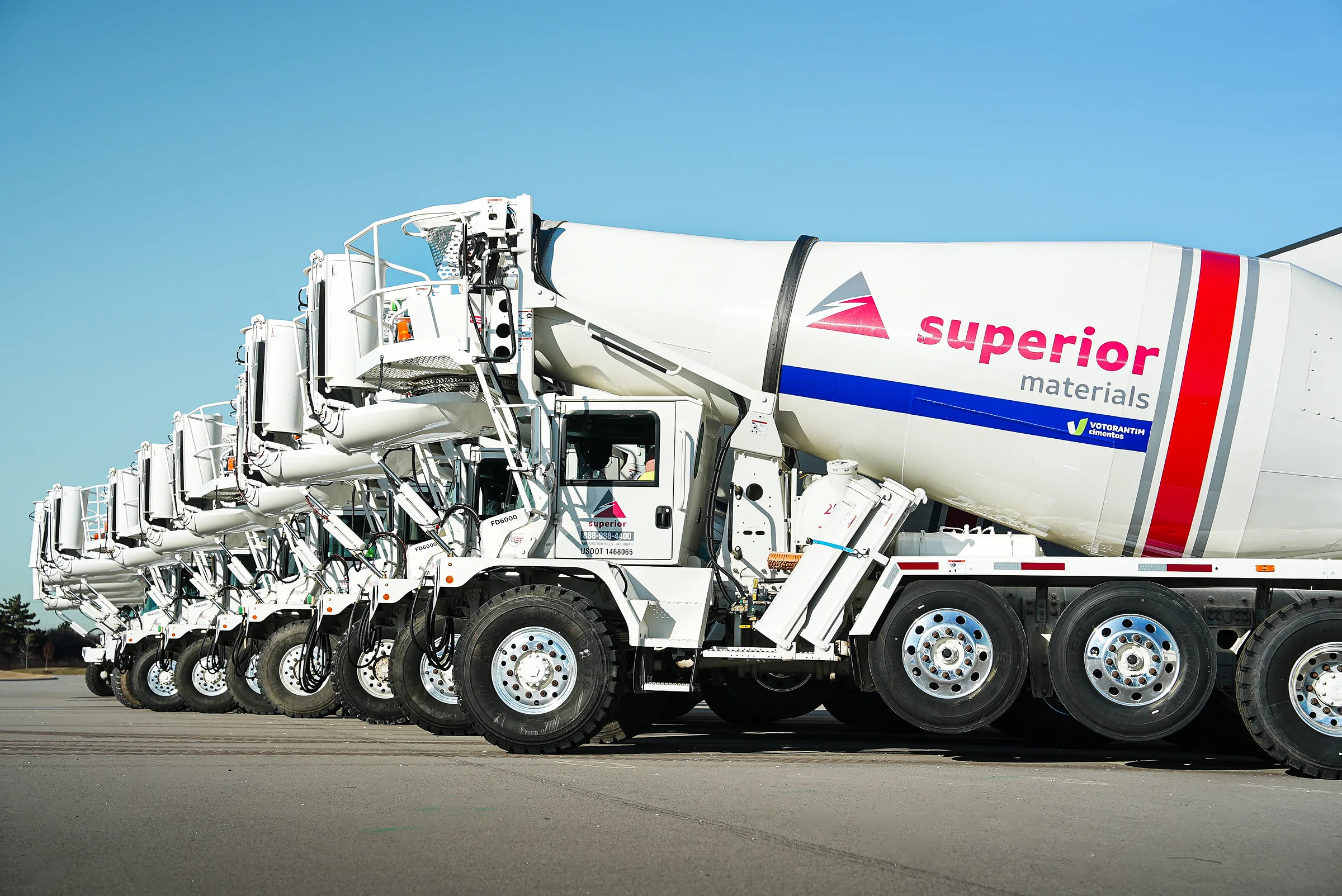 Superior Materials' Ready-mix Concrete - row of white Superior Materials mixer trucks lined up under a blue sky